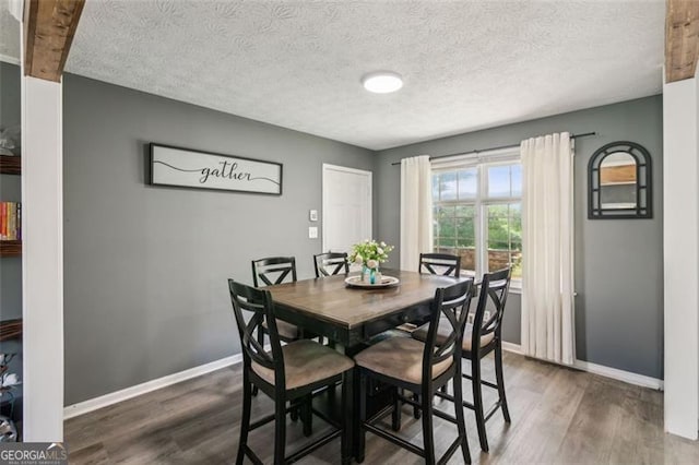 dining area featuring a textured ceiling, baseboards, and dark wood finished floors