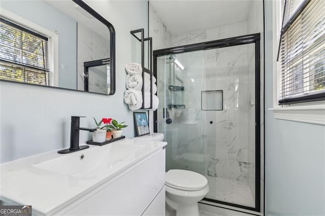 bathroom with toilet, vanity, and a marble finish shower