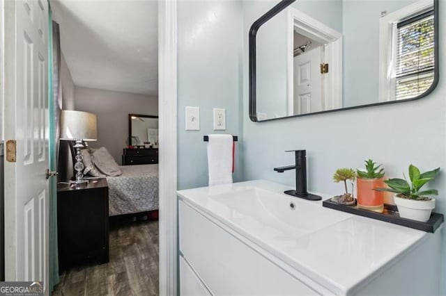 ensuite bathroom with connected bathroom, wood finished floors, and vanity