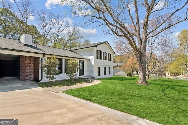view of home's exterior featuring an attached carport, a chimney, concrete driveway, and a yard