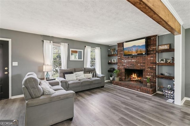living area featuring baseboards, a fireplace, wood finished floors, and a textured ceiling