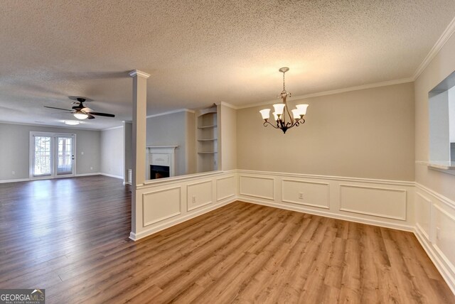 unfurnished dining area with ornamental molding, a textured ceiling, a fireplace, and wood finished floors