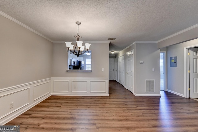 unfurnished dining area featuring a textured ceiling, visible vents, a notable chandelier, and wood finished floors
