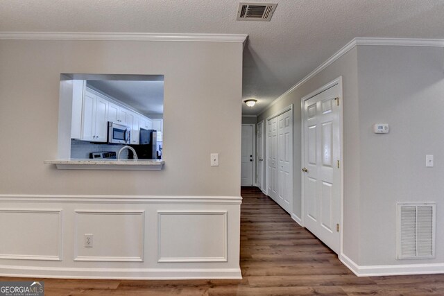 hall featuring a textured ceiling, visible vents, and wood finished floors