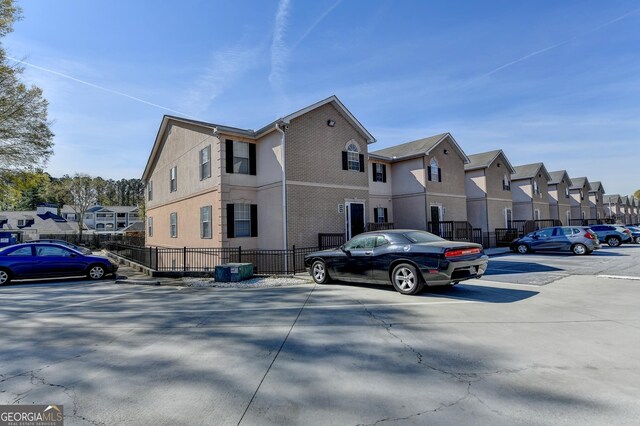 view of side of property featuring a residential view, fence, and uncovered parking