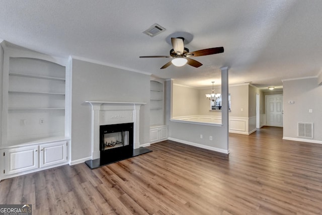 unfurnished living room featuring ceiling fan with notable chandelier, a textured ceiling, built in shelves, and visible vents