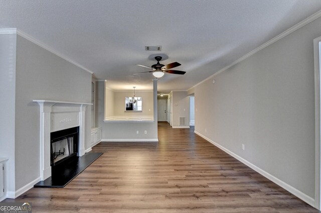 unfurnished living room with ceiling fan with notable chandelier, visible vents, crown molding, and wood finished floors