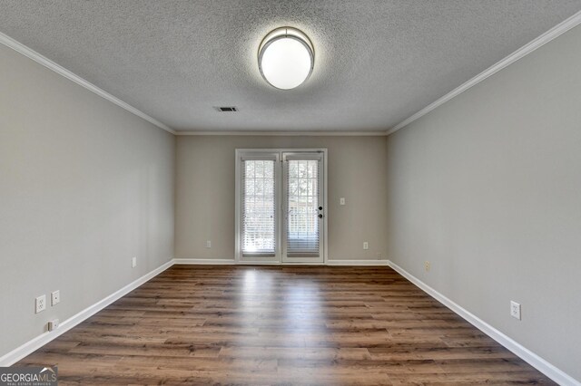 unfurnished room with dark wood-style floors, visible vents, baseboards, and ornamental molding