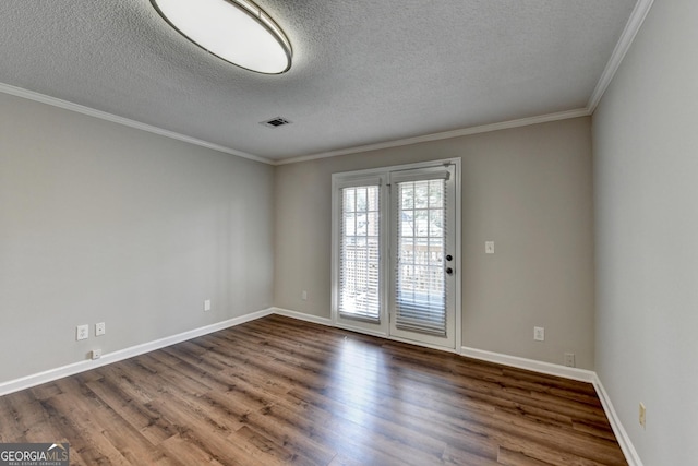 spare room featuring ornamental molding, baseboards, and wood finished floors