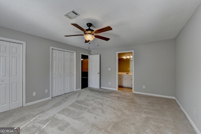 unfurnished bedroom with baseboards, visible vents, multiple closets, and carpet