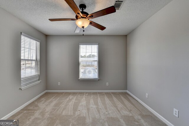empty room featuring light carpet, baseboards, ceiling fan, and a textured ceiling