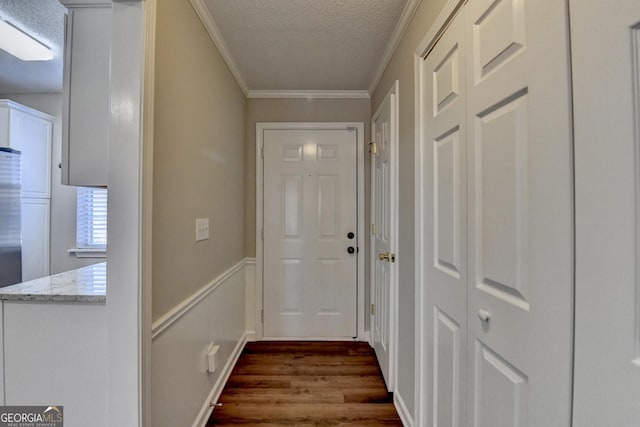 doorway featuring a textured ceiling, ornamental molding, and dark wood finished floors