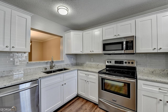 kitchen with white cabinets, a sink, stainless steel appliances, and light wood-type flooring
