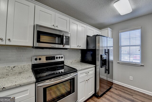 kitchen with a textured ceiling, stainless steel appliances, tasteful backsplash, white cabinetry, and light wood-type flooring
