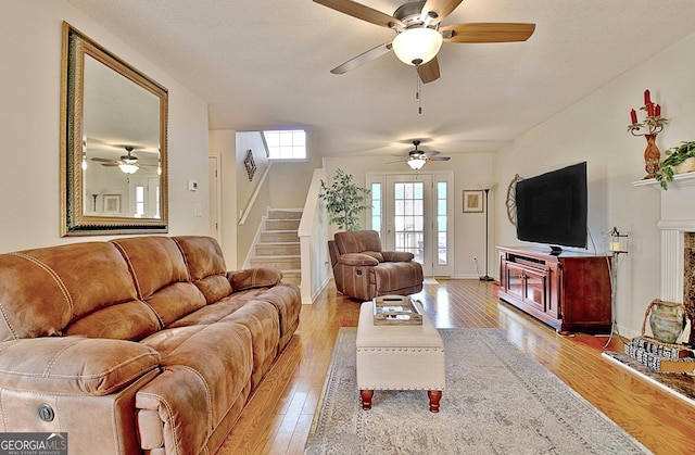 living area with light wood-style floors, a ceiling fan, baseboards, and stairway