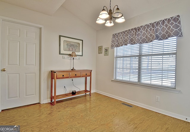 interior space with an inviting chandelier, visible vents, lofted ceiling, baseboards, and light wood finished floors