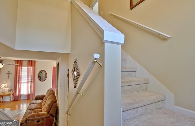 stairway featuring ceiling fan and a high ceiling