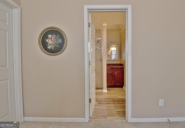 corridor with baseboards and light colored carpet