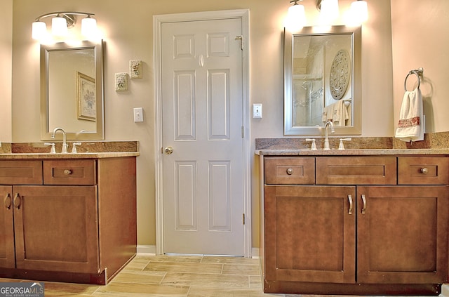full bath featuring baseboards, a sink, and two vanities