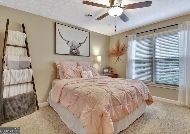 carpeted bedroom with a textured ceiling, baseboards, ceiling fan, and visible vents