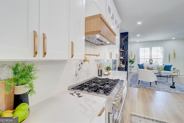 kitchen featuring light countertops, high end stainless steel range, light wood-style floors, white cabinets, and glass insert cabinets