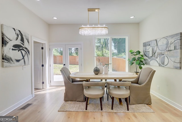 dining area with baseboards, light wood-type flooring, visible vents, and a chandelier