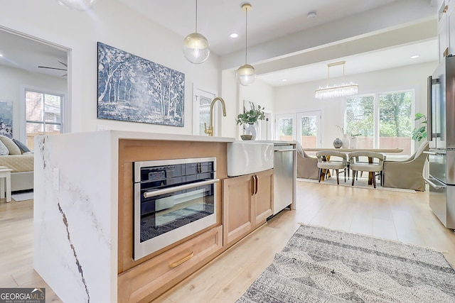 kitchen with light wood finished floors, plenty of natural light, light brown cabinetry, and appliances with stainless steel finishes
