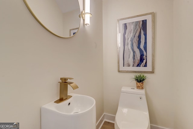 bathroom with baseboards, a sink, and toilet