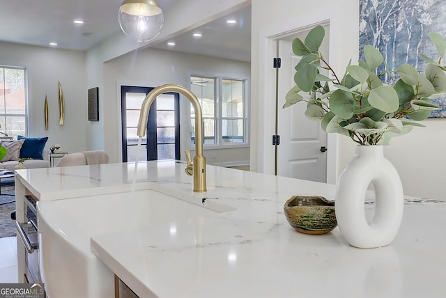 kitchen featuring a sink, open floor plan, light stone counters, and recessed lighting