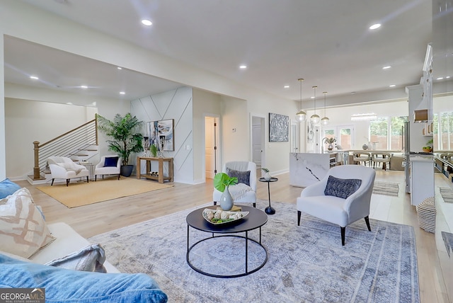 living room featuring baseboards, stairway, light wood finished floors, and recessed lighting