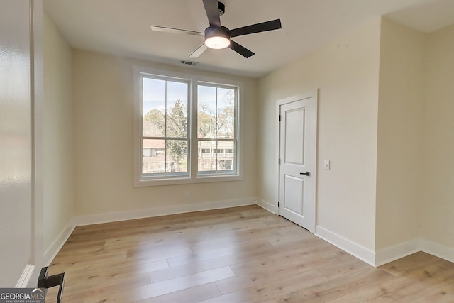 spare room featuring baseboards, ceiling fan, visible vents, and light wood finished floors