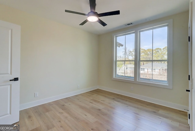 empty room featuring a ceiling fan, baseboards, and light wood finished floors