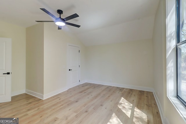 empty room with lofted ceiling, a ceiling fan, a healthy amount of sunlight, and light wood-type flooring