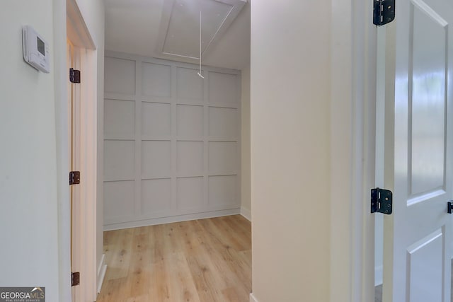 walk in closet with attic access and light wood finished floors