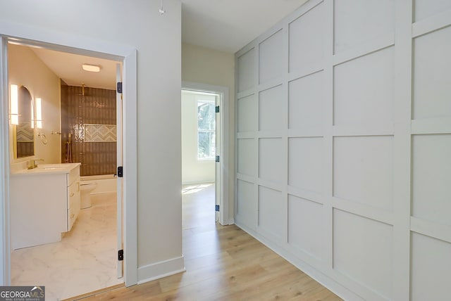 corridor featuring a sink and light wood finished floors