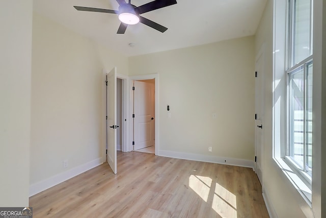 spare room featuring baseboards, ceiling fan, and light wood-style flooring
