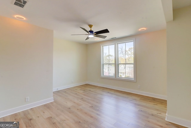 spare room with light wood-type flooring, a ceiling fan, baseboards, and visible vents