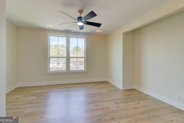 spare room featuring a ceiling fan, visible vents, baseboards, and light wood-type flooring
