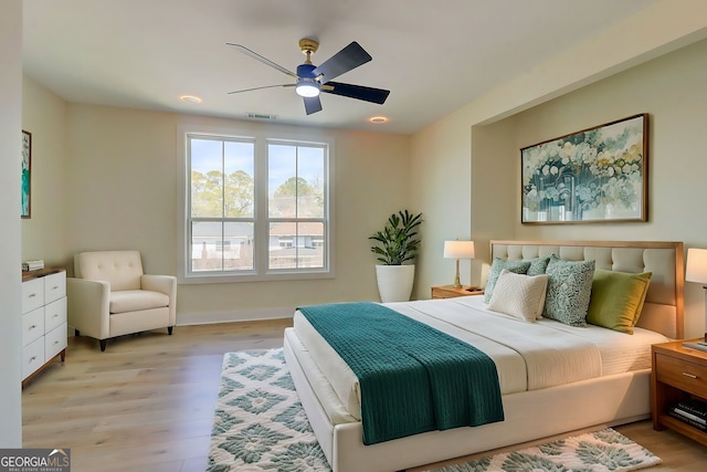 bedroom with baseboards, visible vents, a ceiling fan, and light wood finished floors