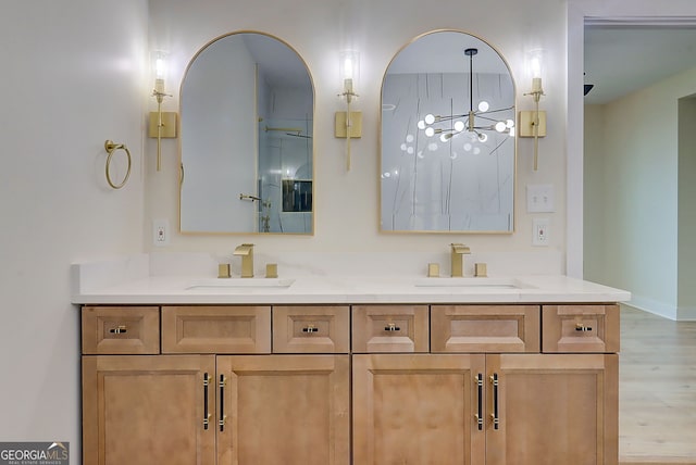 full bathroom featuring double vanity, a notable chandelier, wood finished floors, and a sink