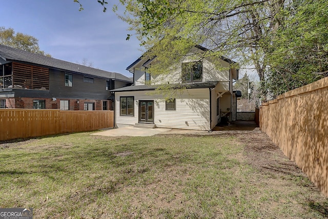 rear view of property with a fenced backyard, a yard, and a patio area