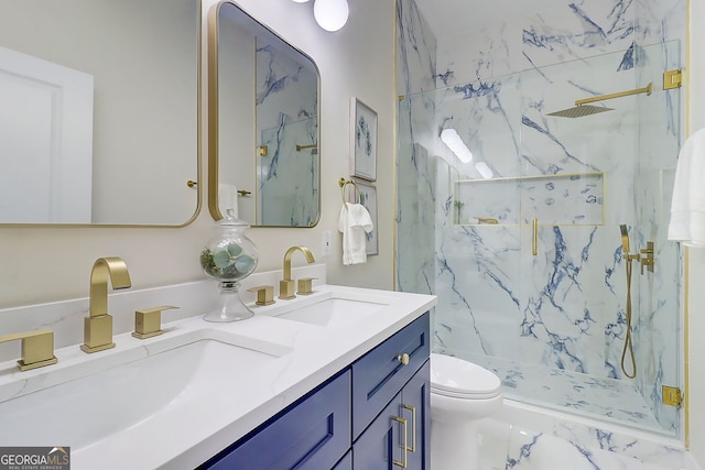 full bath featuring a marble finish shower, double vanity, a sink, and toilet
