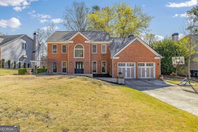 colonial inspired home featuring a front lawn, driveway, a garage, and brick siding