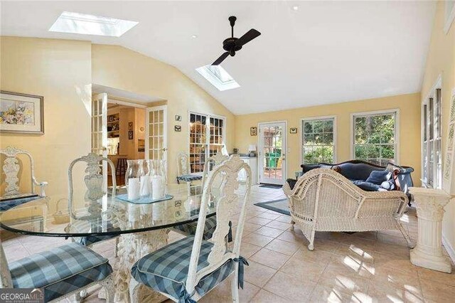dining room featuring vaulted ceiling with skylight and light tile patterned floors