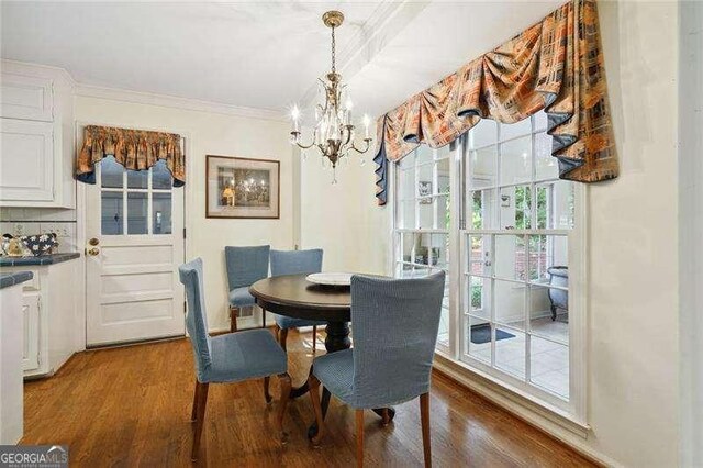 dining room featuring ornamental molding, wood finished floors, and an inviting chandelier
