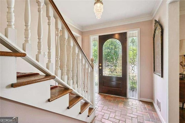foyer with baseboards, stairs, brick floor, and crown molding