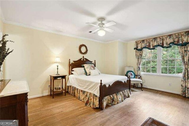 bedroom featuring crown molding, baseboards, and light wood finished floors