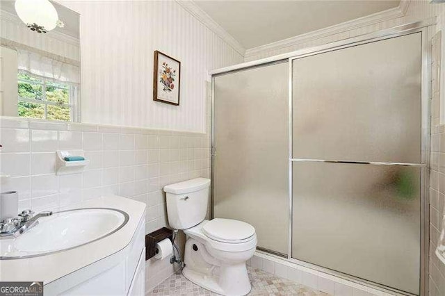full bathroom with a stall shower, toilet, vanity, and a wainscoted wall