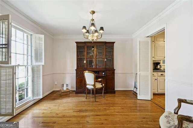 sitting room with ornamental molding, a chandelier, and wood finished floors