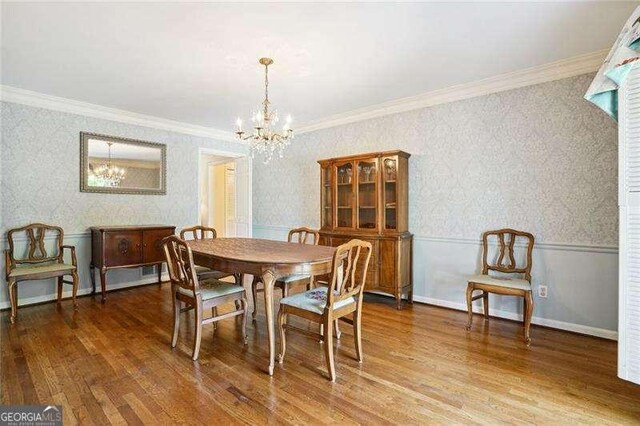 dining space with wallpapered walls, wood finished floors, a notable chandelier, and wainscoting